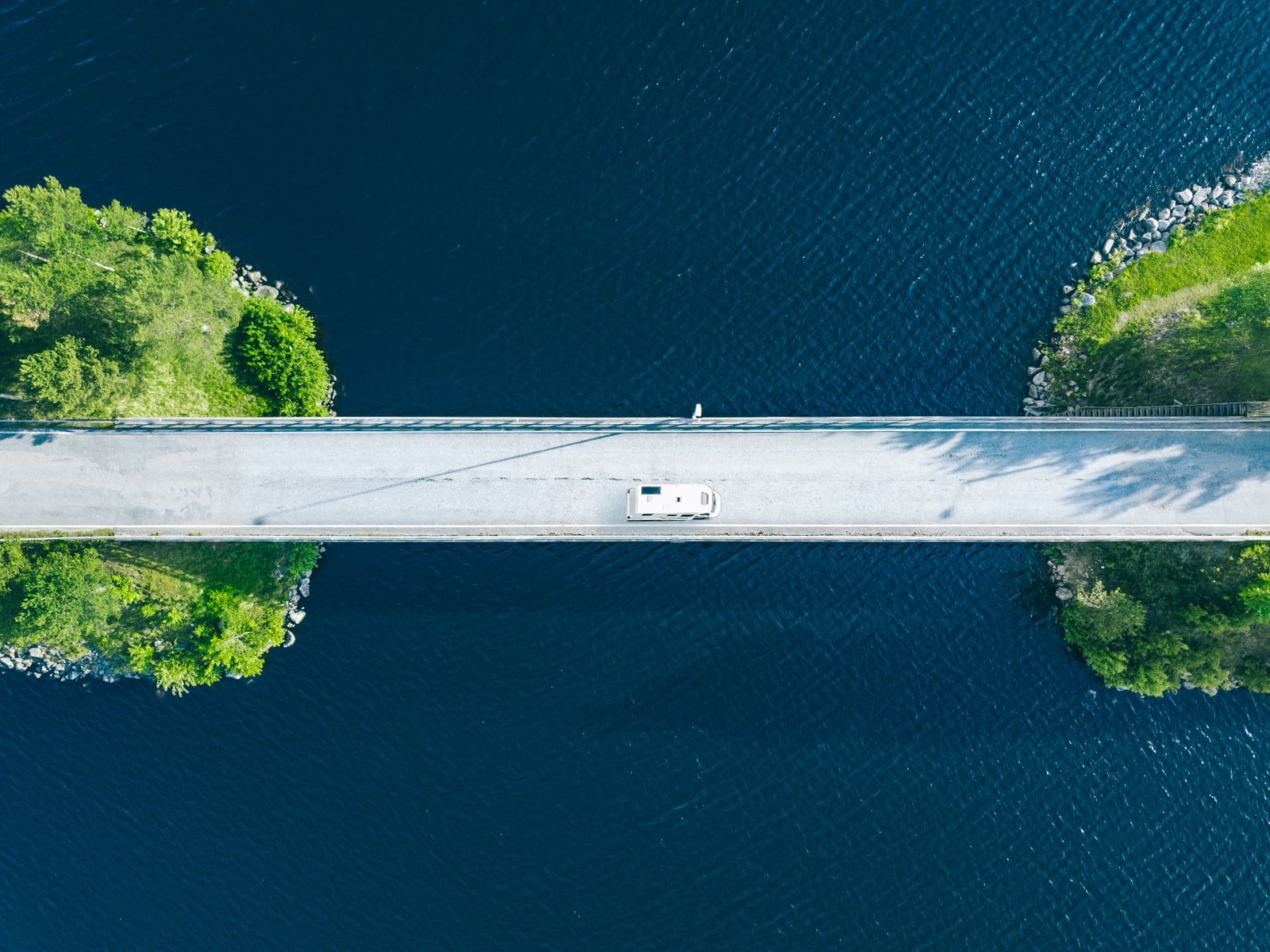 Aerial view of a camper crossing a bridge over water